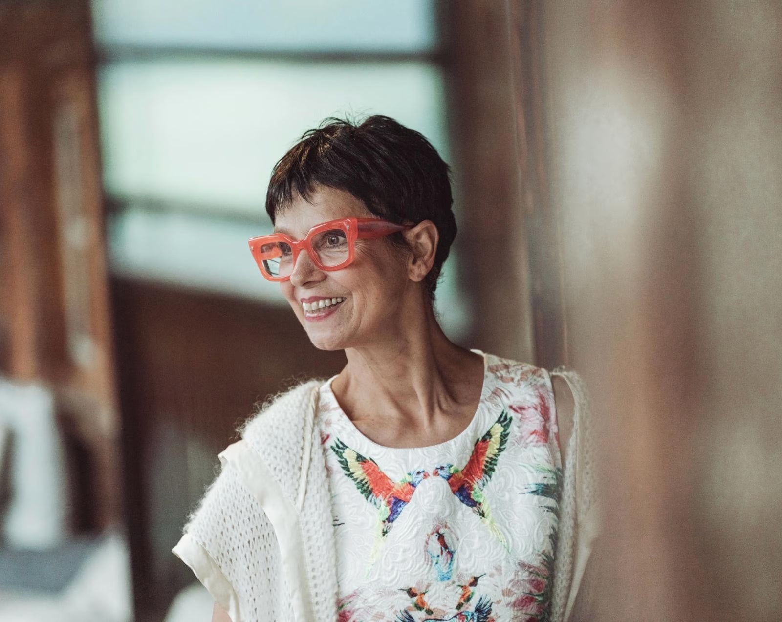 Die seitlich fotografierte Künstlerin Barbara Bollerhoff in hellem Kleid mit oranger Brille lacht