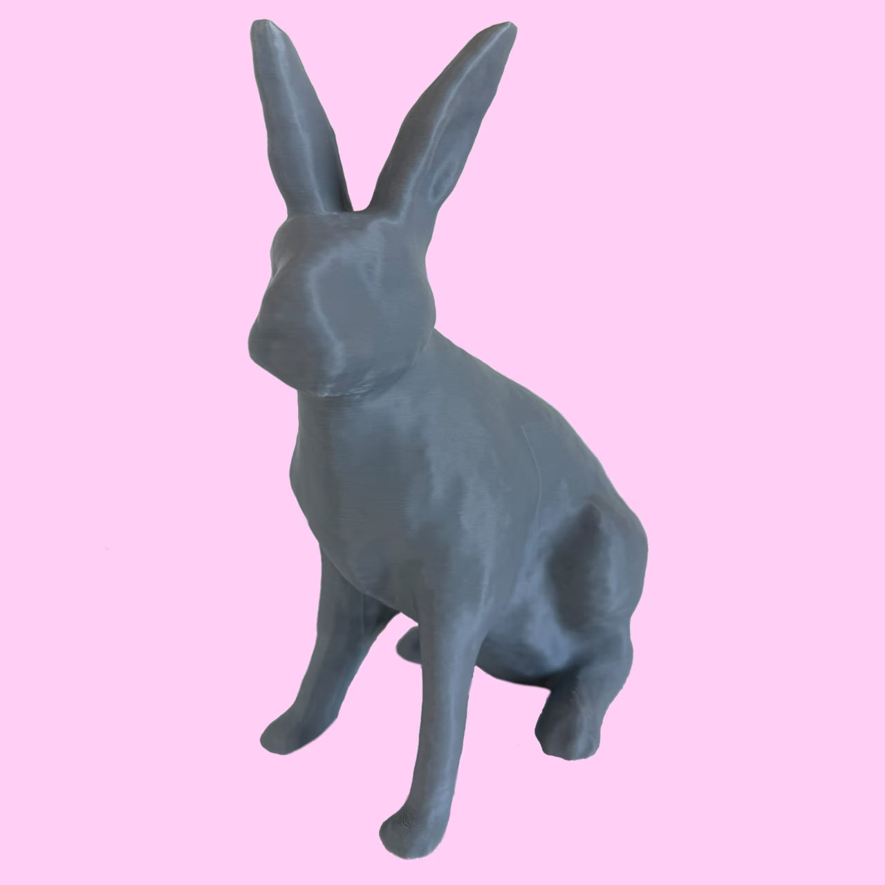 3D-gedruckter Hase in grau sitzt vor rosa Hintergrund