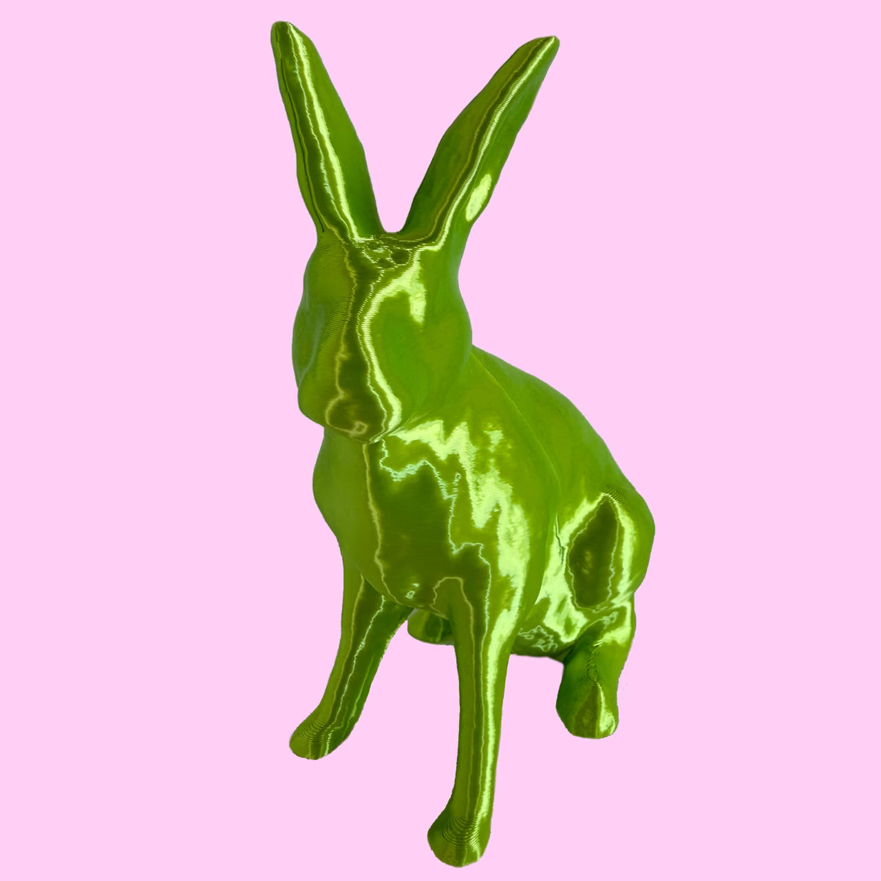 3D-gedruckter Hase in grün glänzend sitzt vor rosa Hintergrund