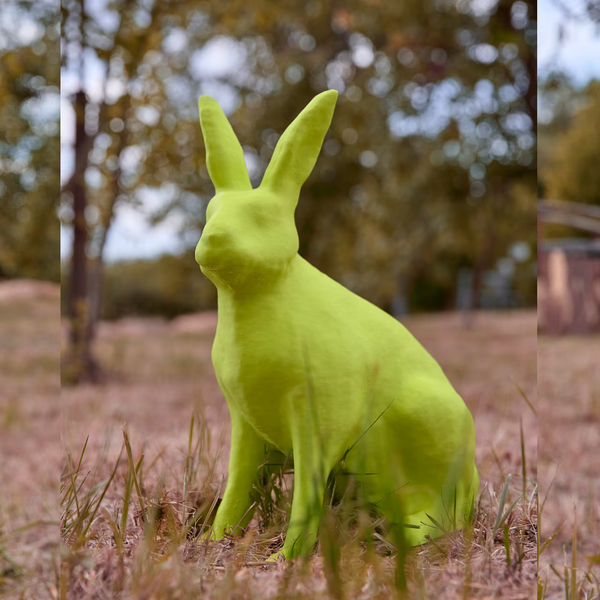 3D-gedruckter Hase in limettengrün sitzt im Gras