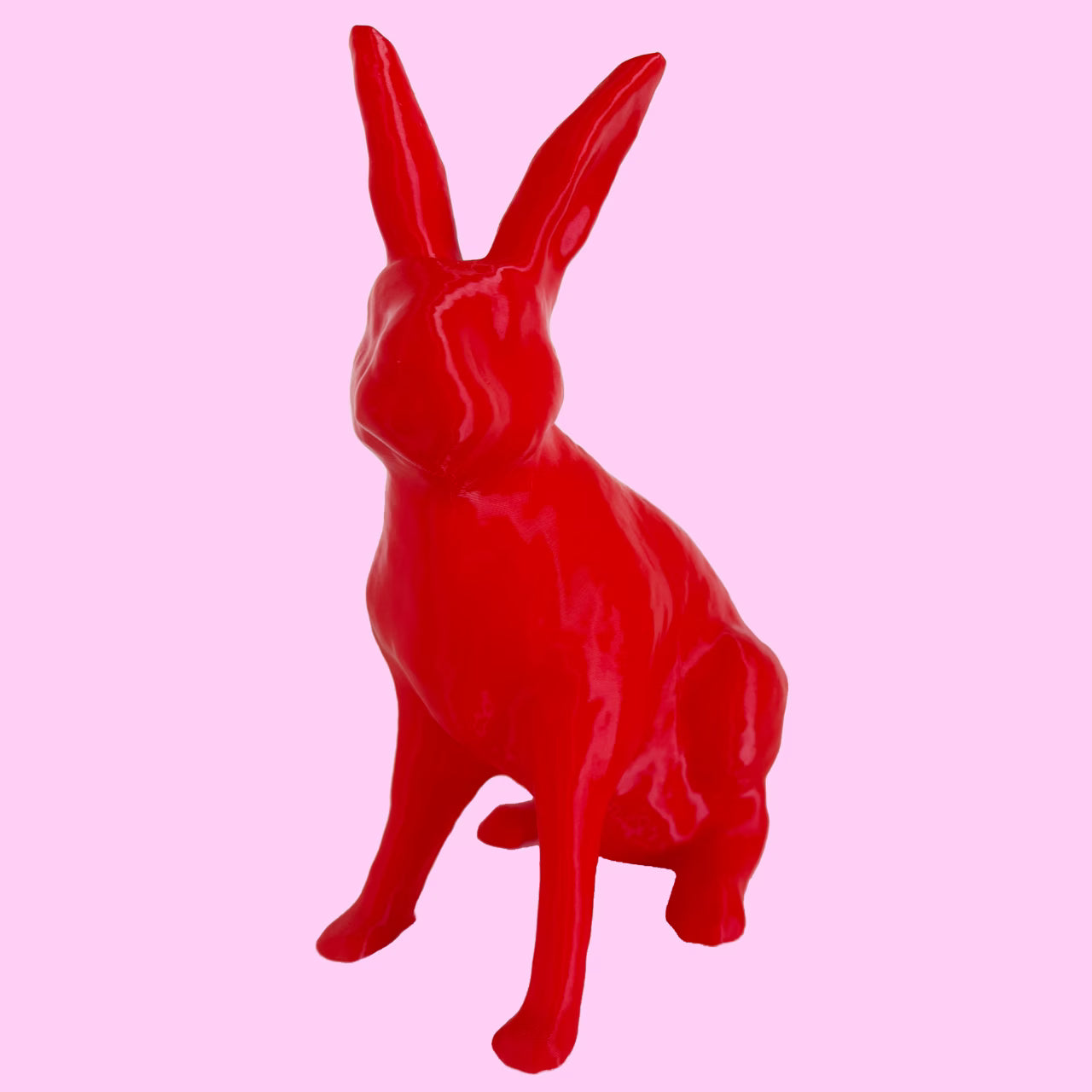 3D-gedruckter Hase in rot sitzt vor rosa Hintergrund