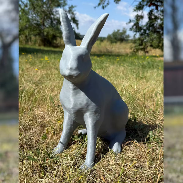 3D-gedruckter Hase in grau sitzt im Gras