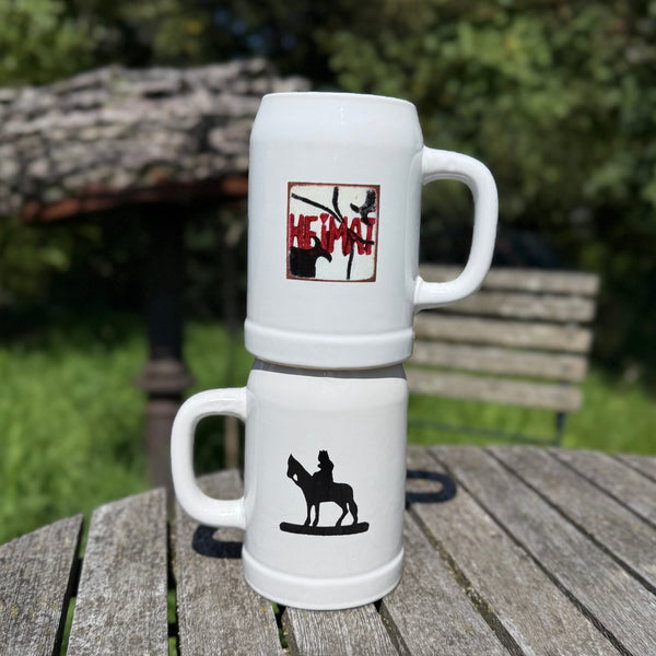Zwei weiße Bierkrüge mit Heimat und Bamberger Reiter Print stehen auf Holztisch