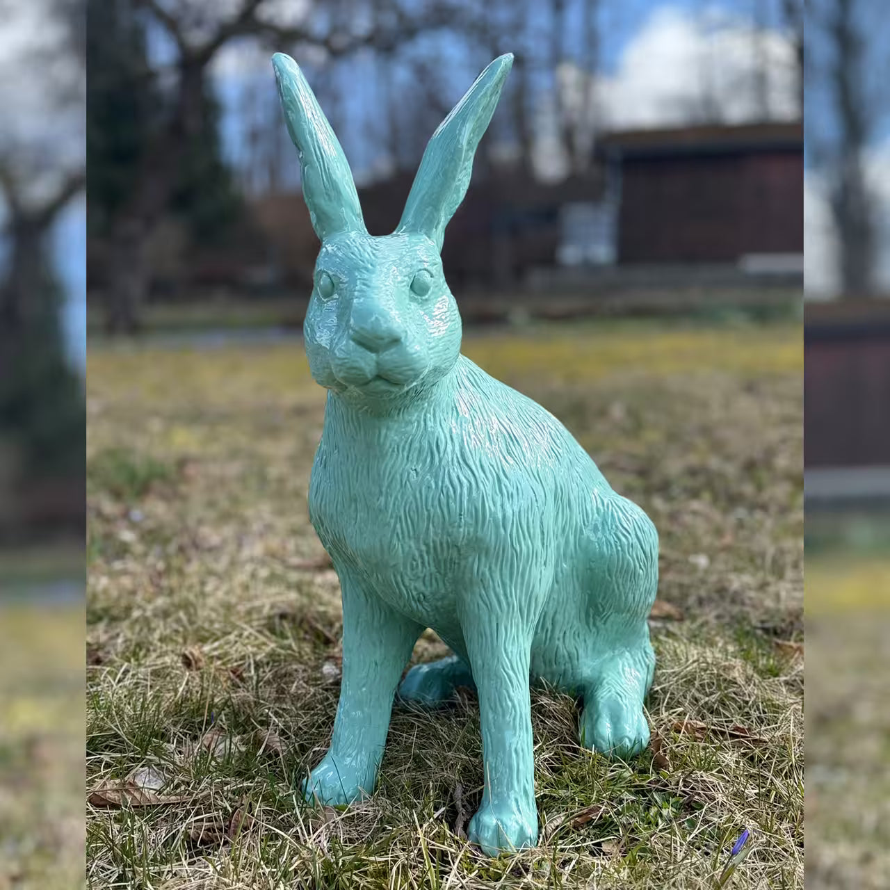 Mintgrüne Hasenfigur sitzt im Gras