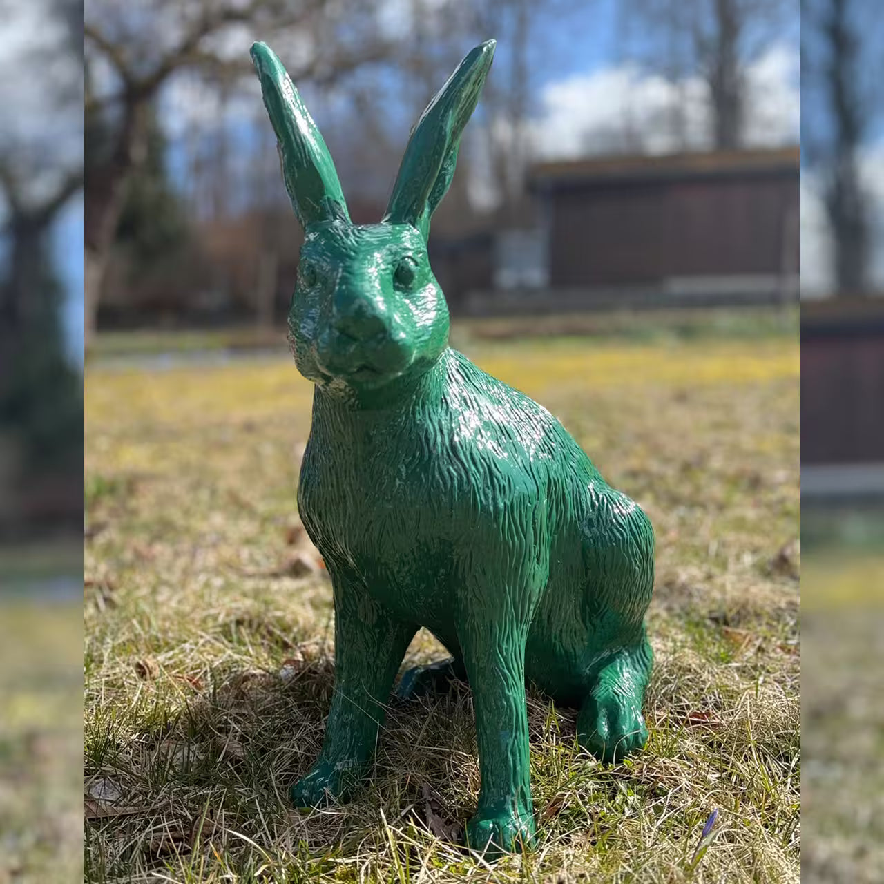 Moosgrüne Hasenfigur sitzt im Gras