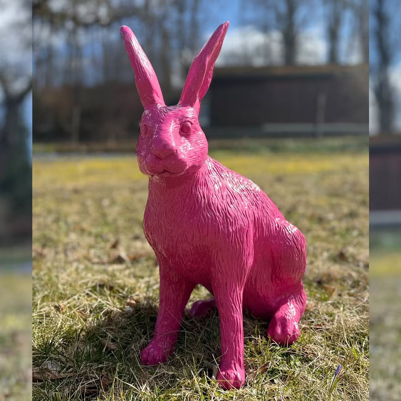 Pinke Hasenfigur sitzt im Gras