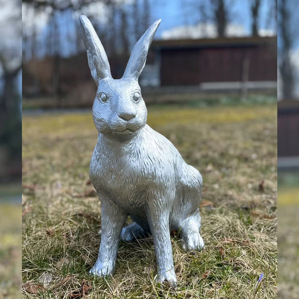 Silberne Hasenfigur sitzt im Gras