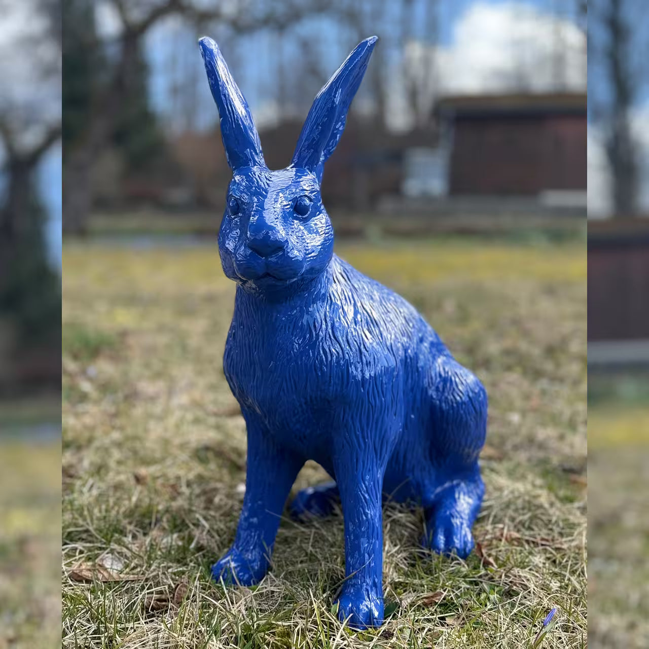 Ultramarinblaue Hasenfigur sitzt im Gras