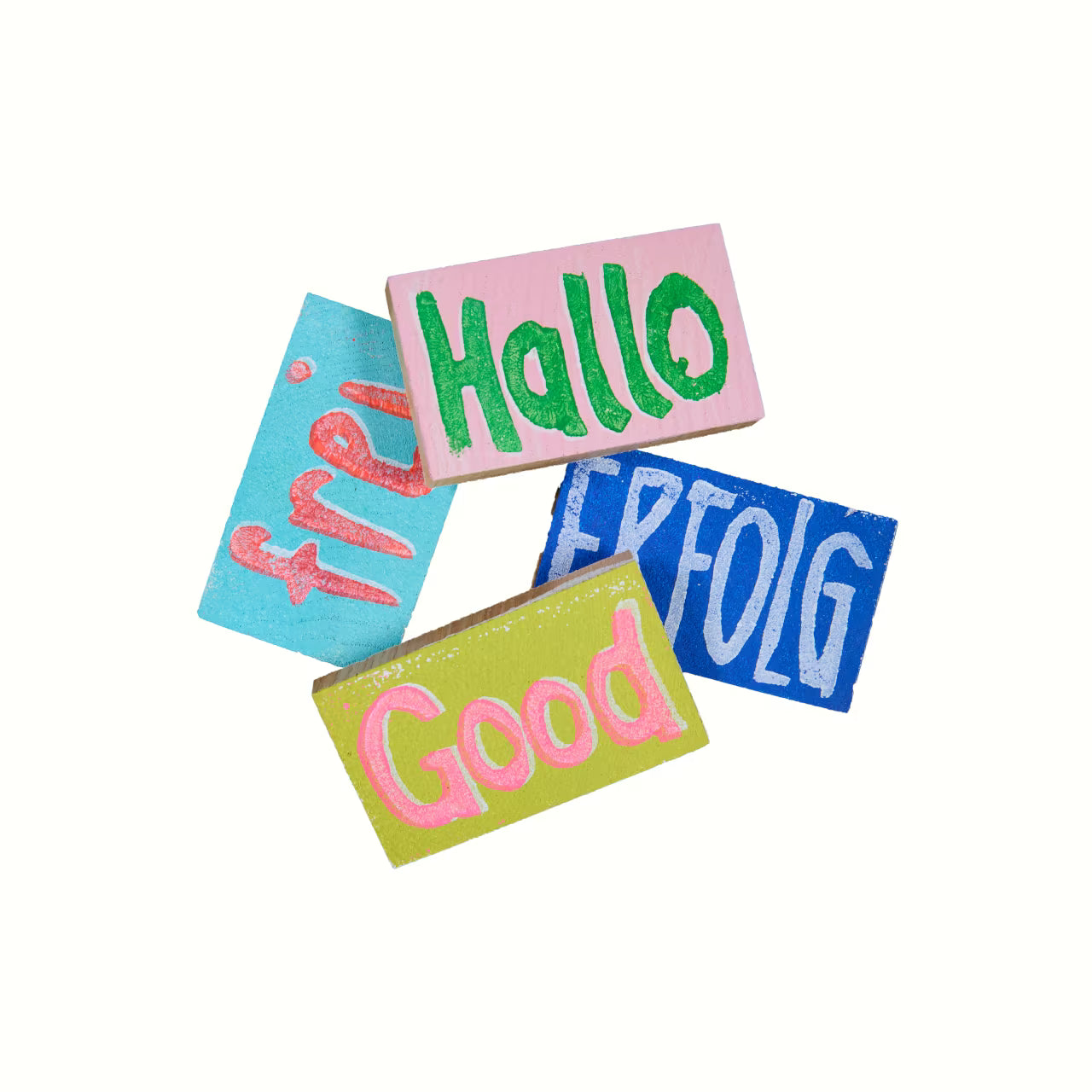 4 Holztäfelchen in bunten Farben mit den Prints "Hallo", "Erfolg", "frei" und "Good" vor weißem Hintergrund
