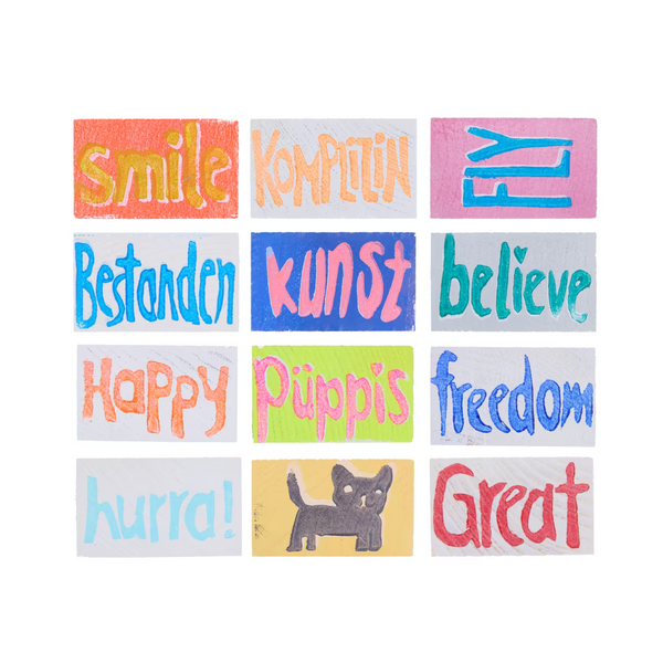 Übersicht über 12 Holztäfelchen in bunten Farben mit den Prints smile, Komplizin, FLY, Bestanden, Kunst, believe, Happy, Püppis, freedom, hurra!, Katzen-Motiv, Great